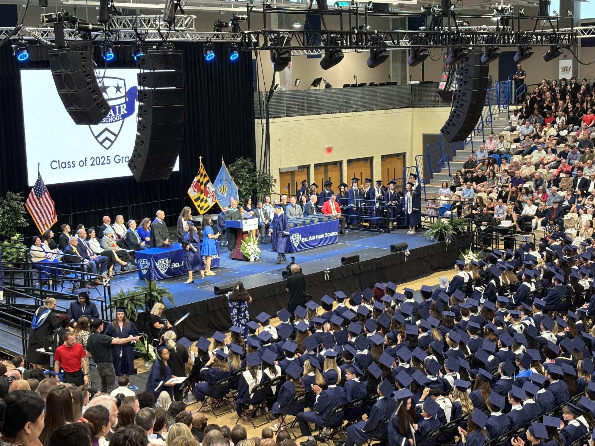 High school graduation ceremony in an arena with a stage, podium and overhead sound system