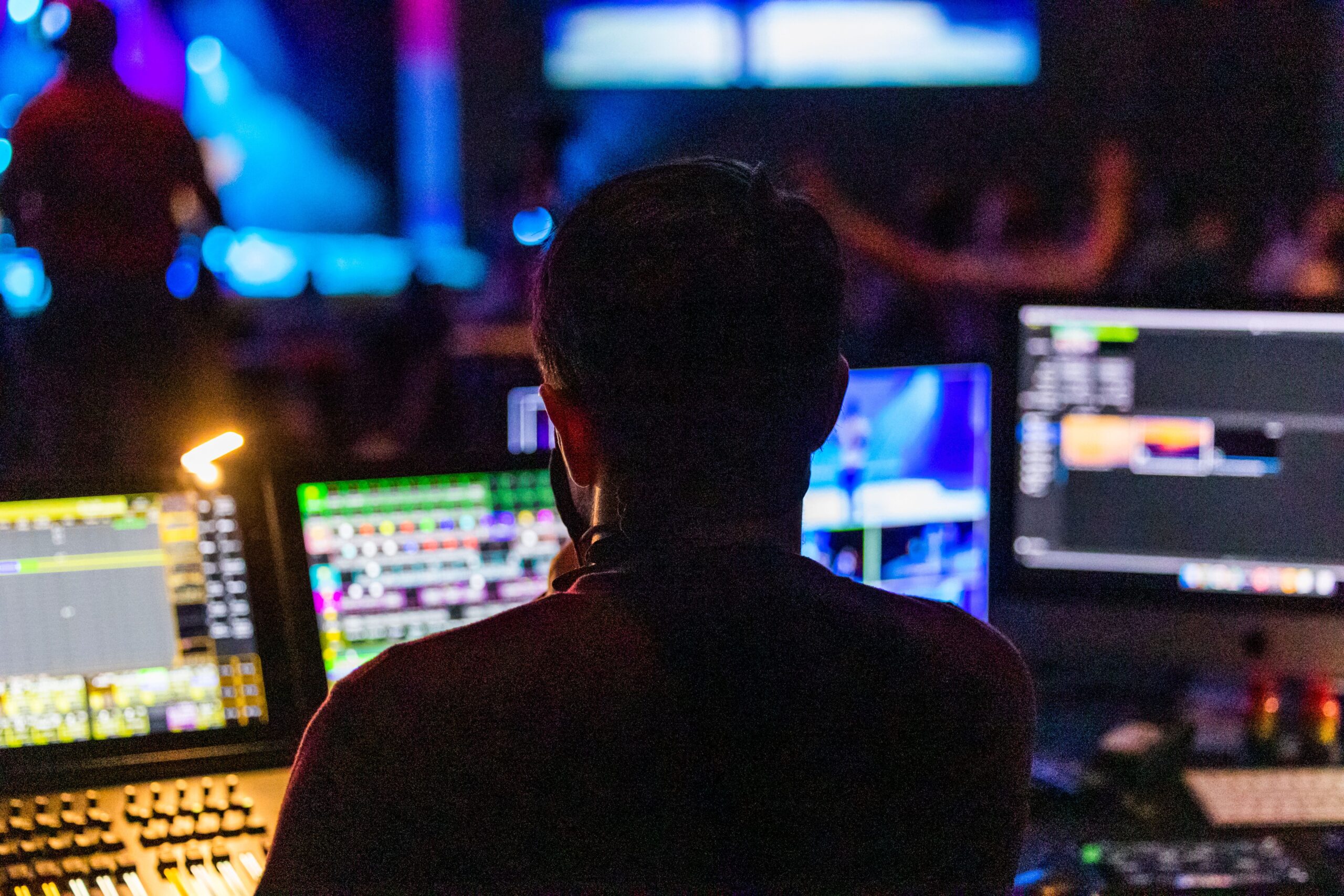 Live event technician at a control desk facing a concert stage
