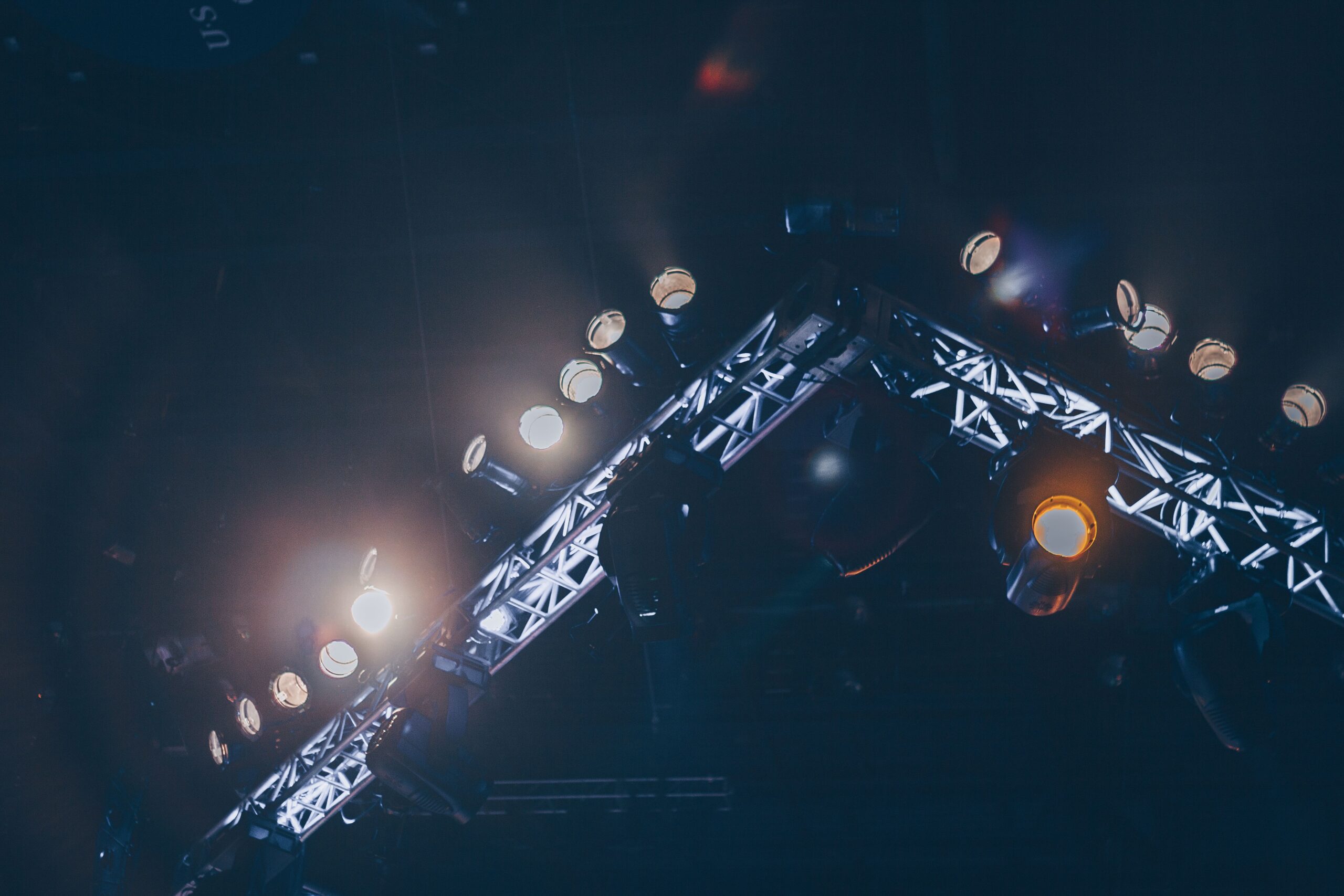 Professional stage lighting fixtures mounted on illuminated truss.